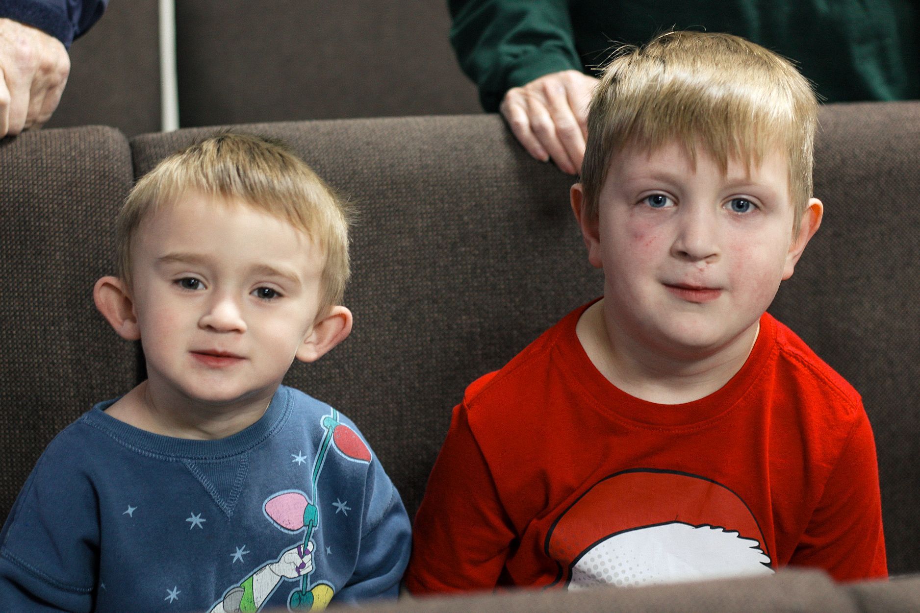Two young boys are sitting next to each other on a couch.