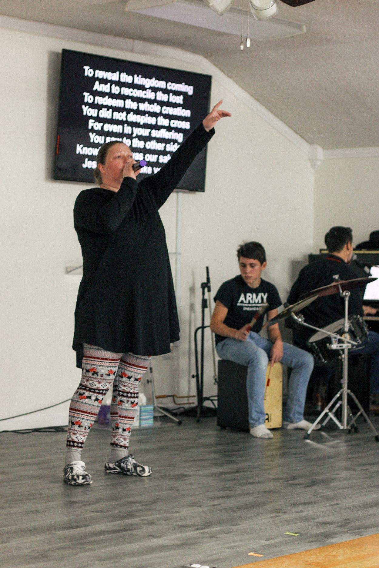 A woman singing into a microphone in front of a sign that says army