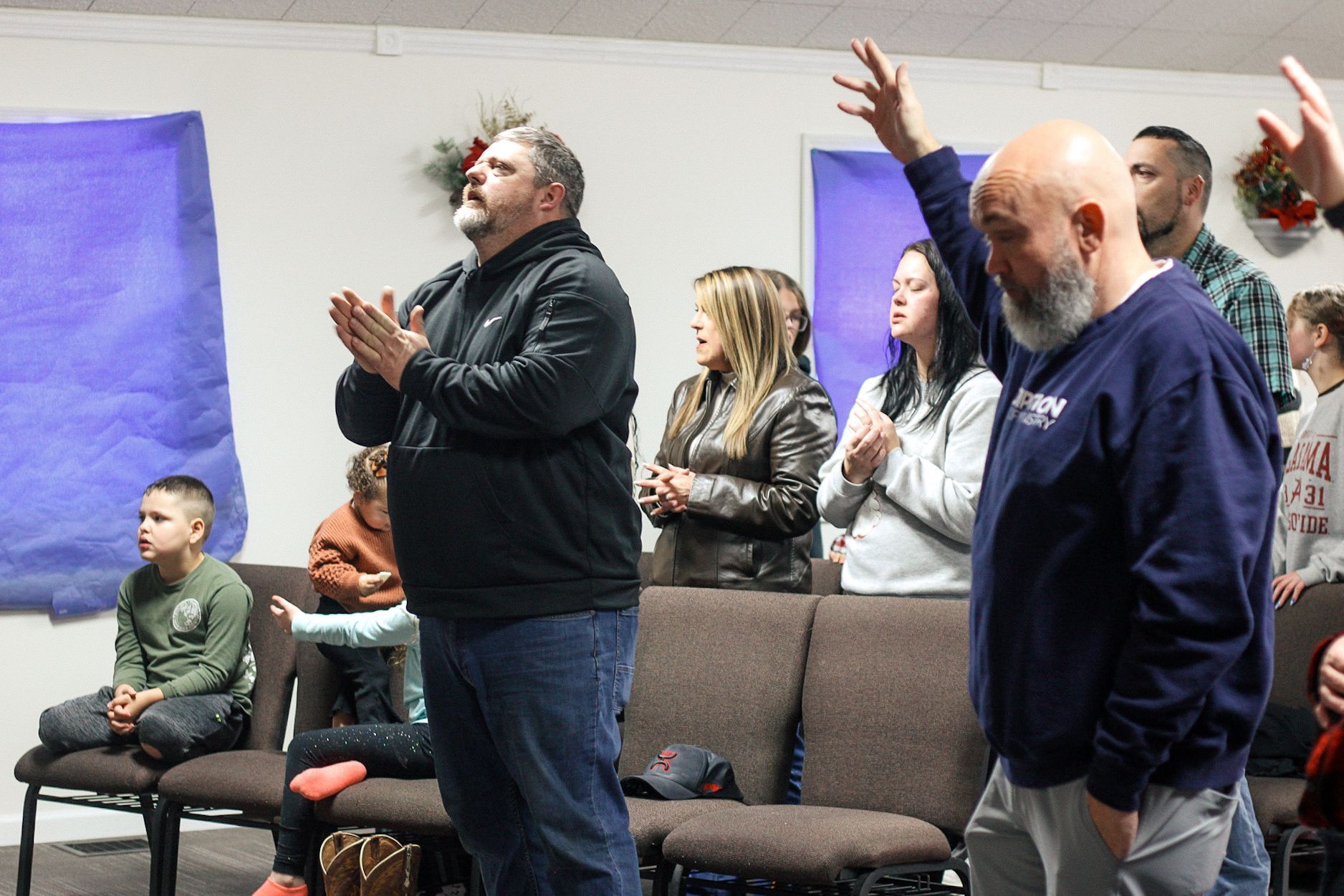 A group of people are standing in a room with their hands in the air.