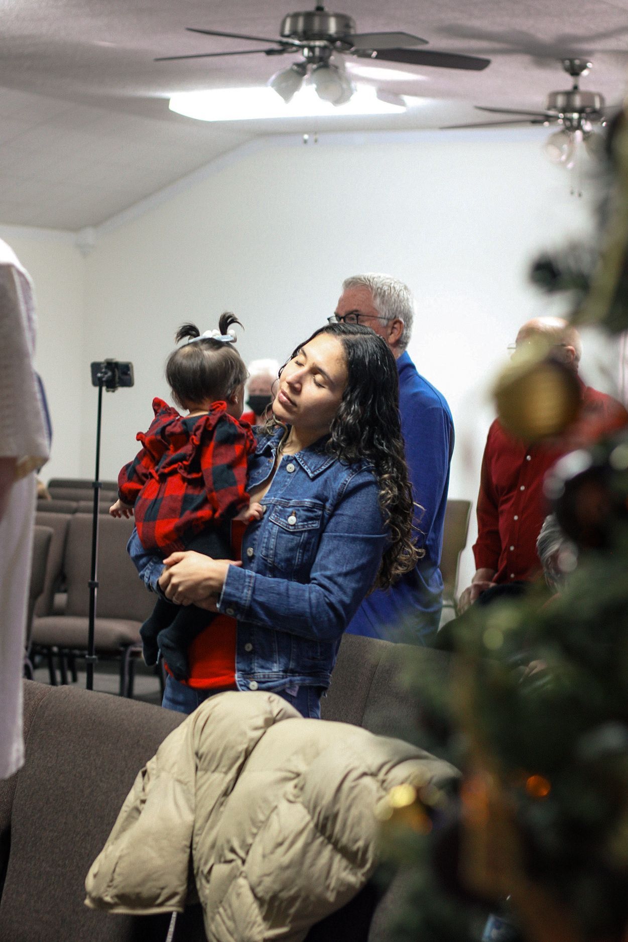 A woman is holding a baby in her arms in a church.