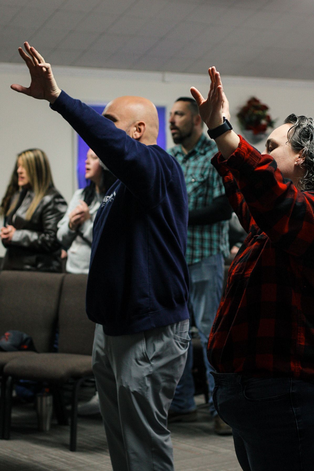 A group of people are standing in a room with their hands in the air.