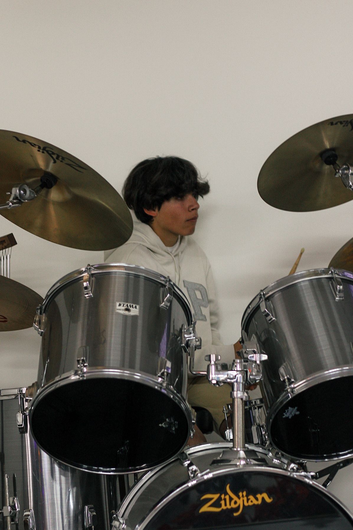 A young man is playing a zildjian drum set.
