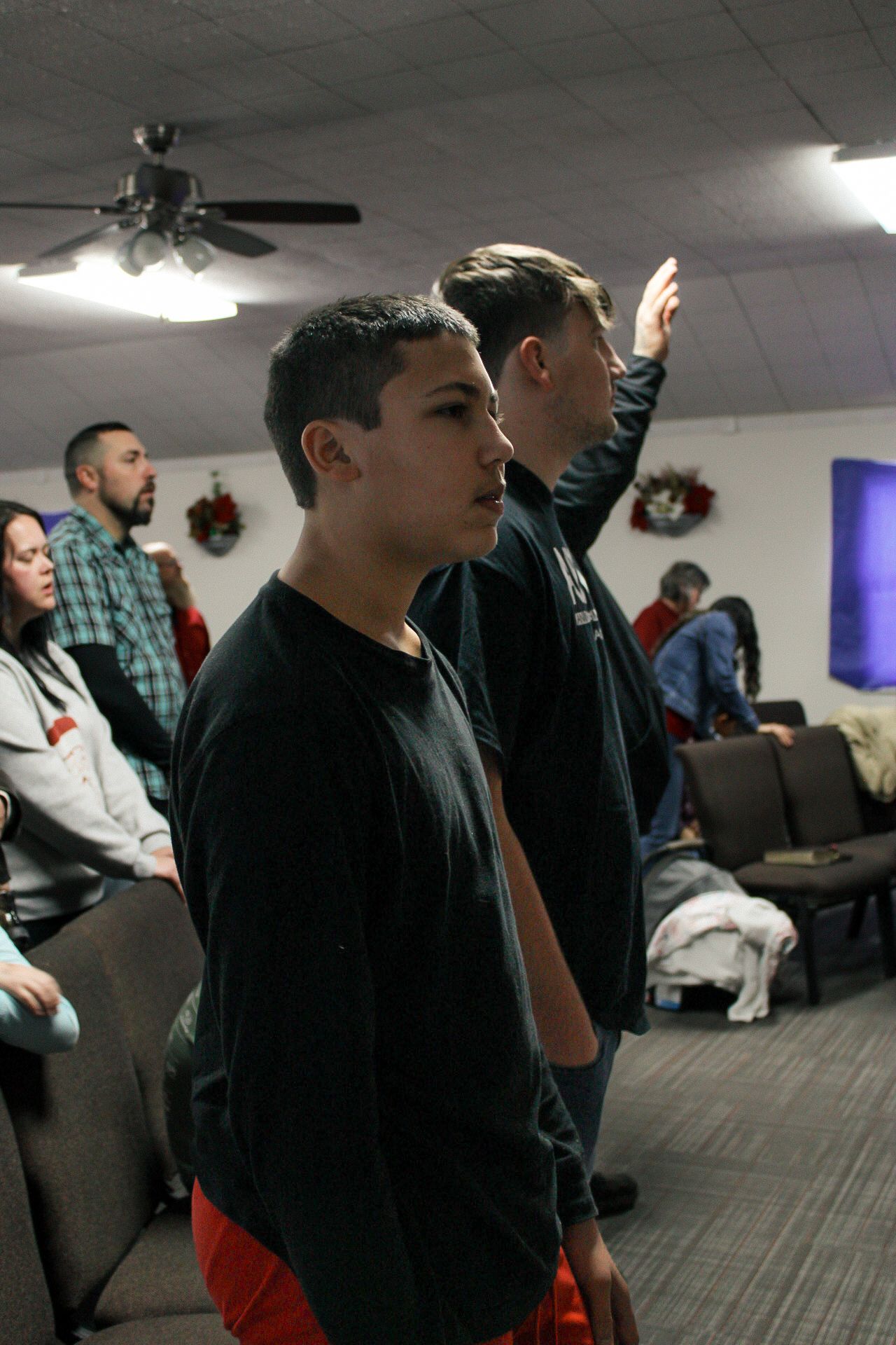 A group of people are standing in a room with a ceiling fan.