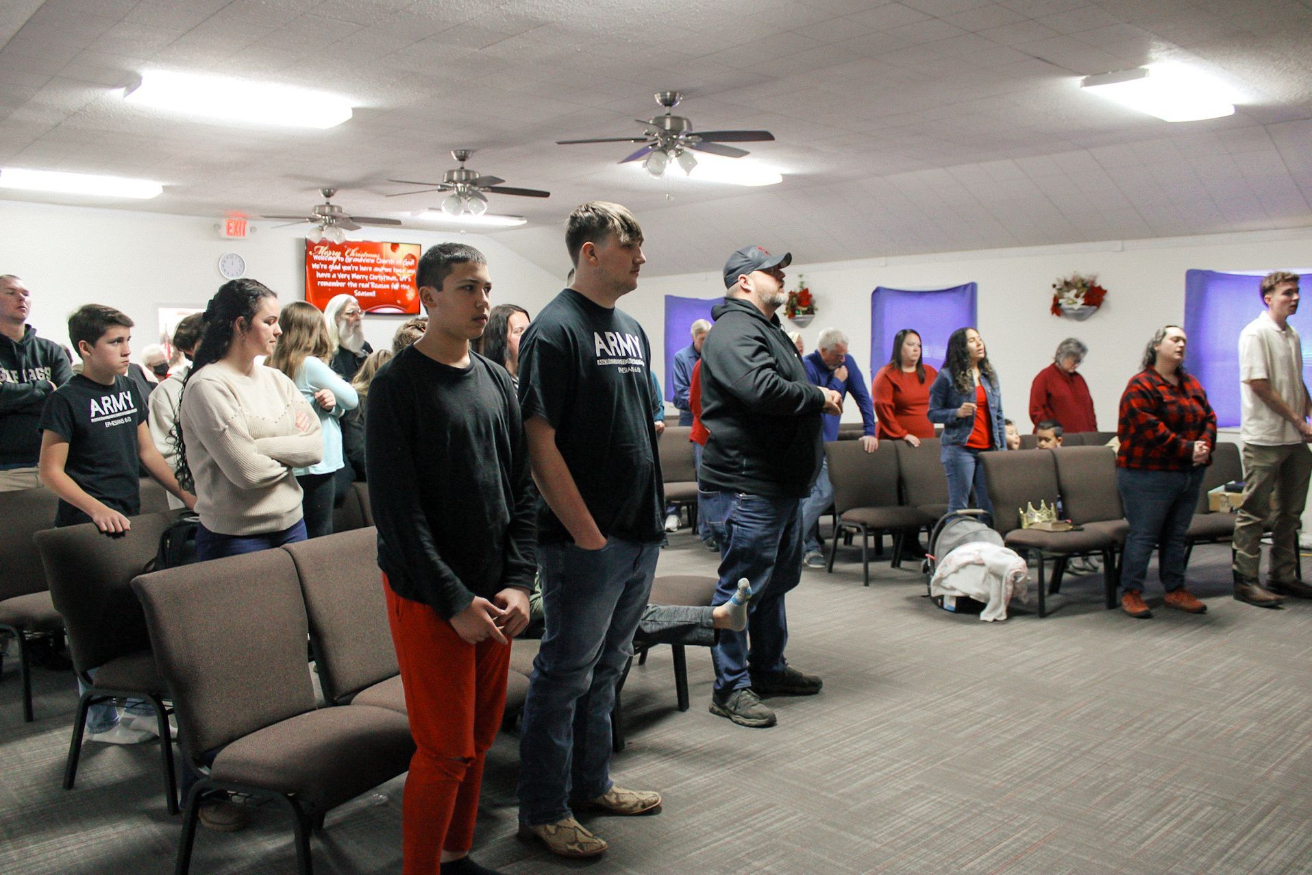 A group of people are standing in a room with chairs.