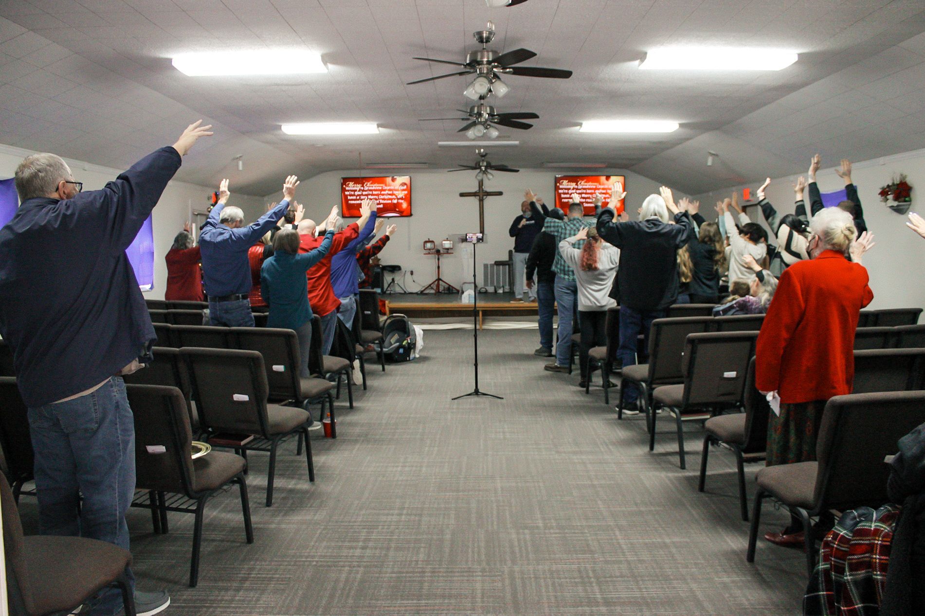 A group of people are standing in a church with their arms in the air.
