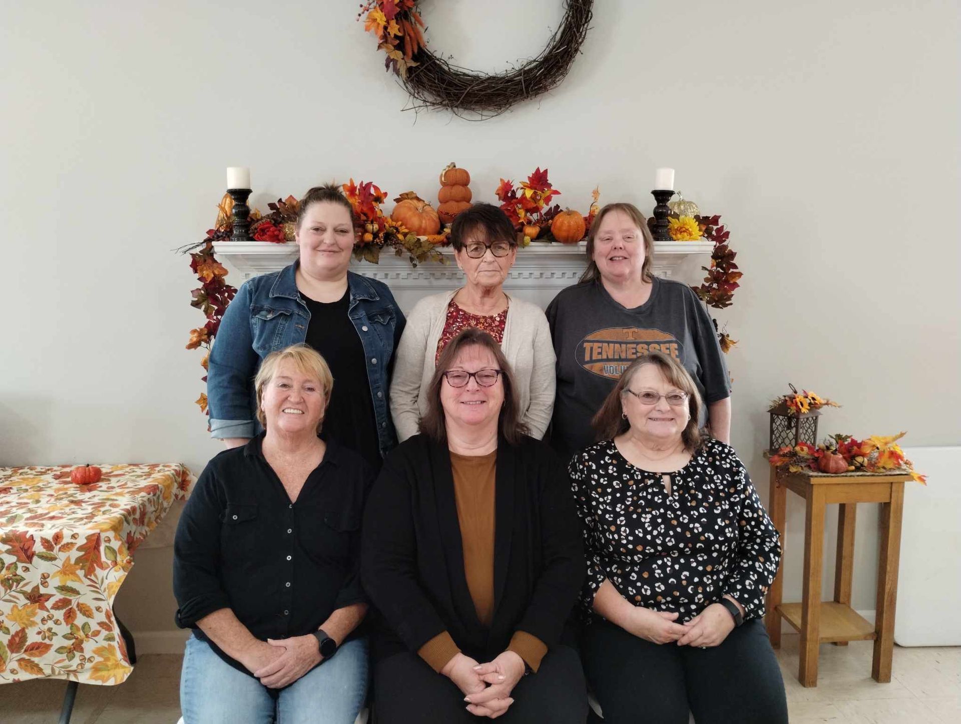 A group of women are posing for a picture in front of a fireplace.