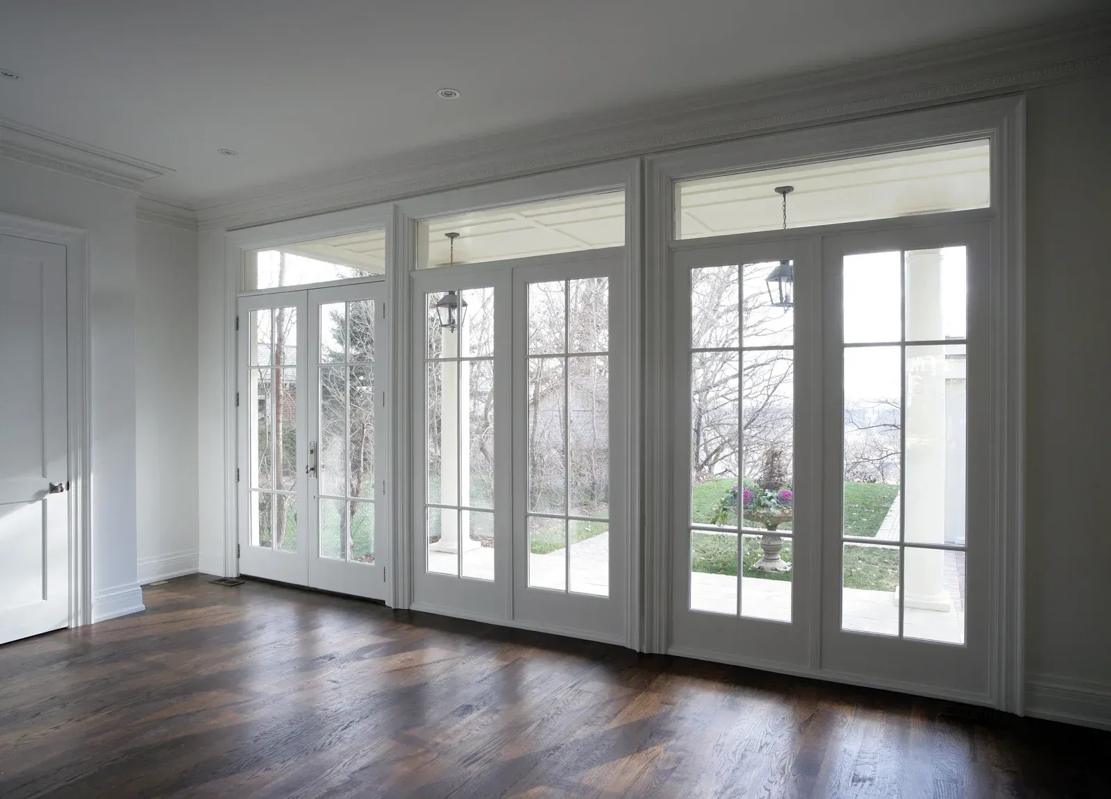 Interior view of room with dark wood floor and large white French doors leading outside.
