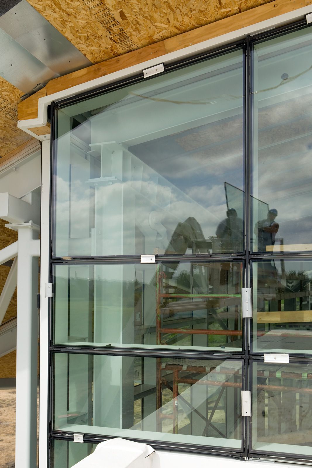 Bright, modern hallway with floor-to-ceiling windows showing a cityscape. Sunlight streams in.