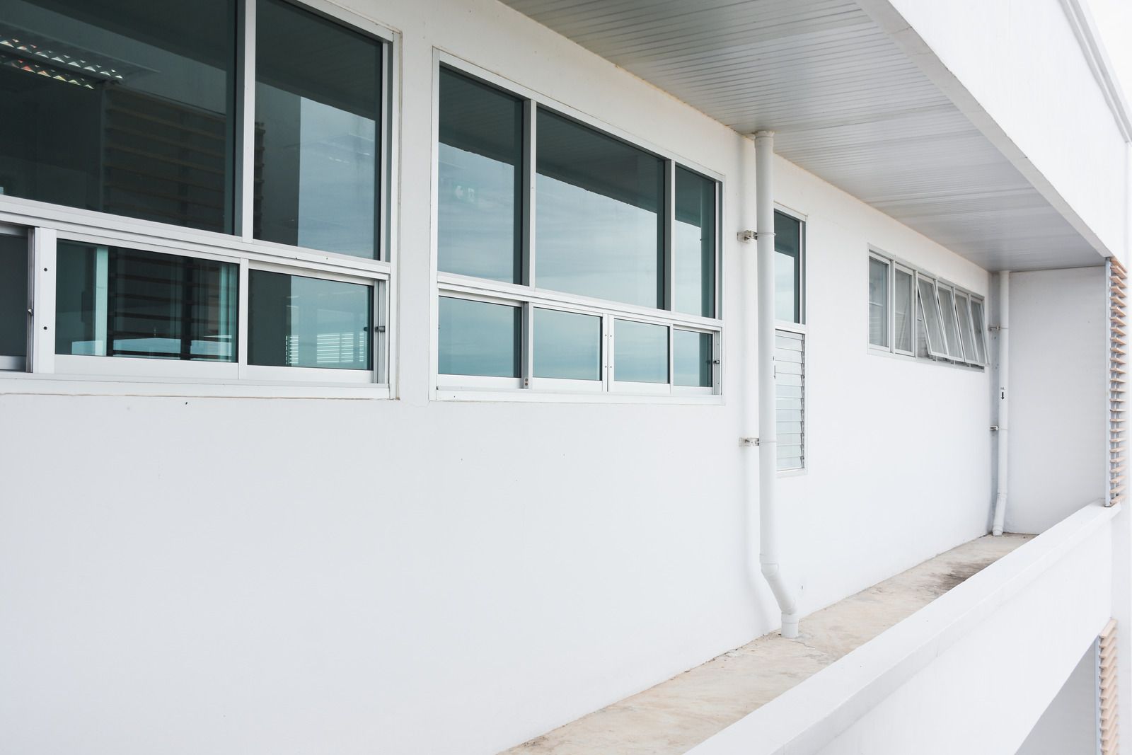 Room with a glass block wall, window, blue floor, and open doorway, overlooking a city.