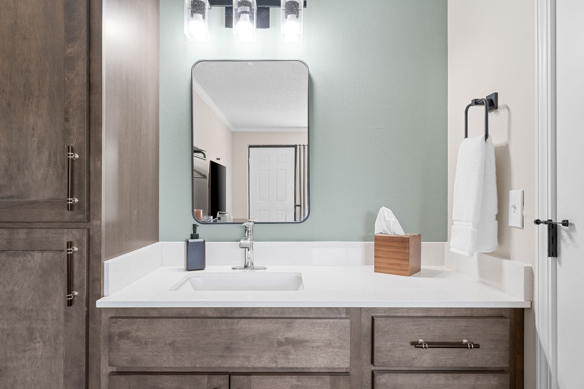 A bathroom with a sink , mirror and cabinets.