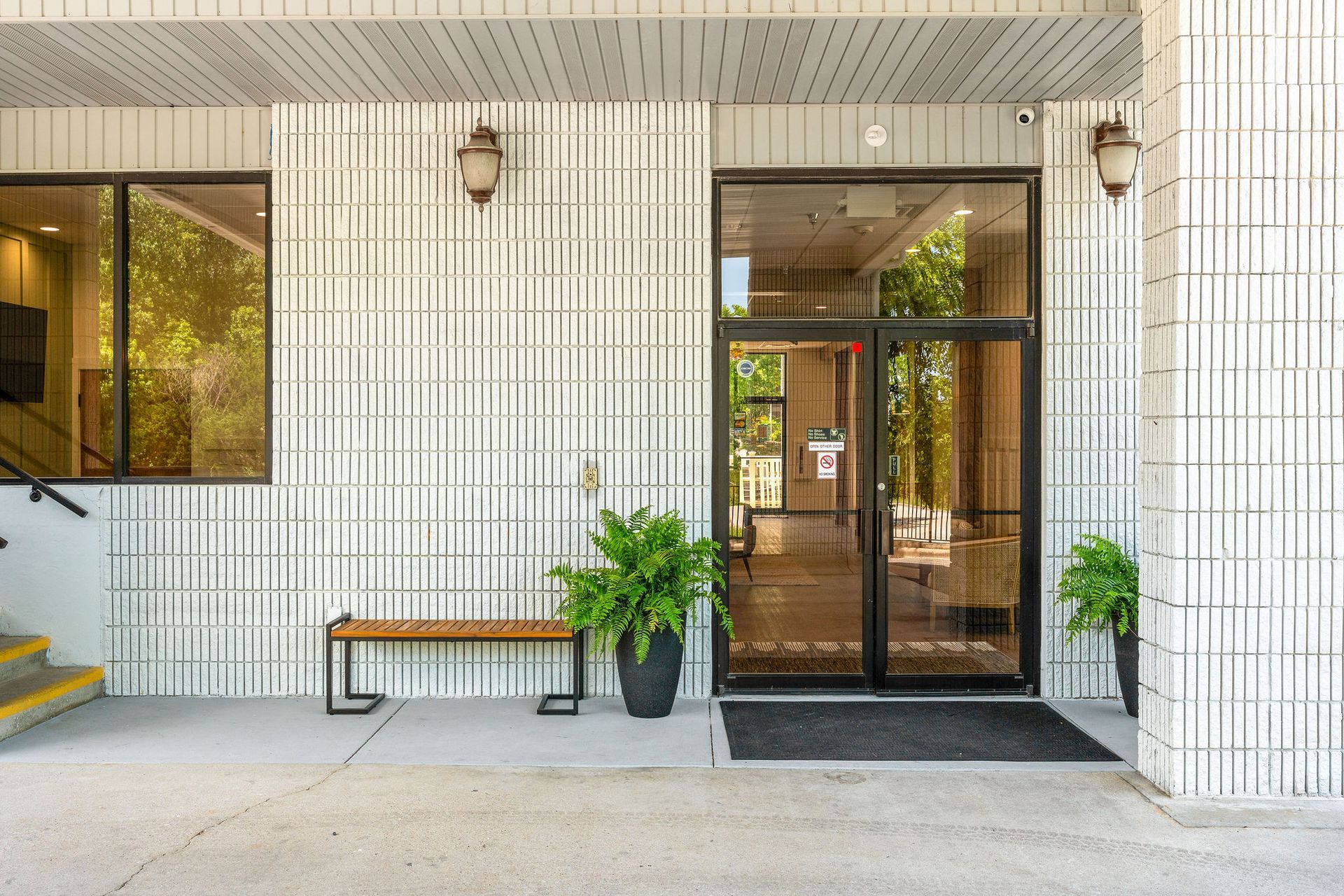 The entrance to a building with a bench and plants in front of it.