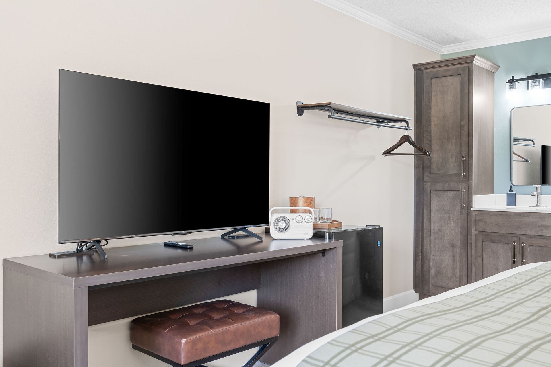A hotel room with a bed , desk , television and mirror.