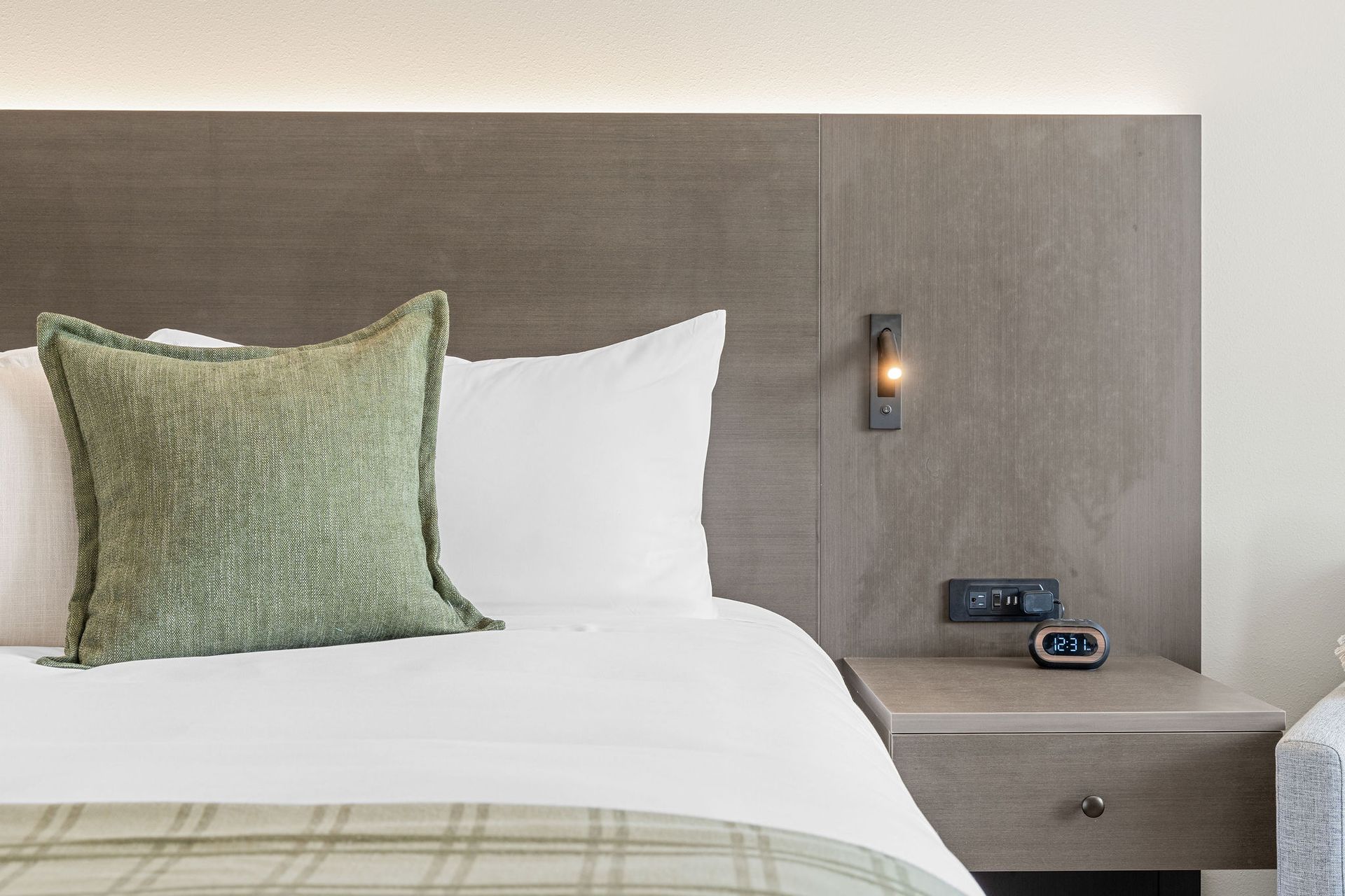 A hotel room with a bed , nightstand , and clock.