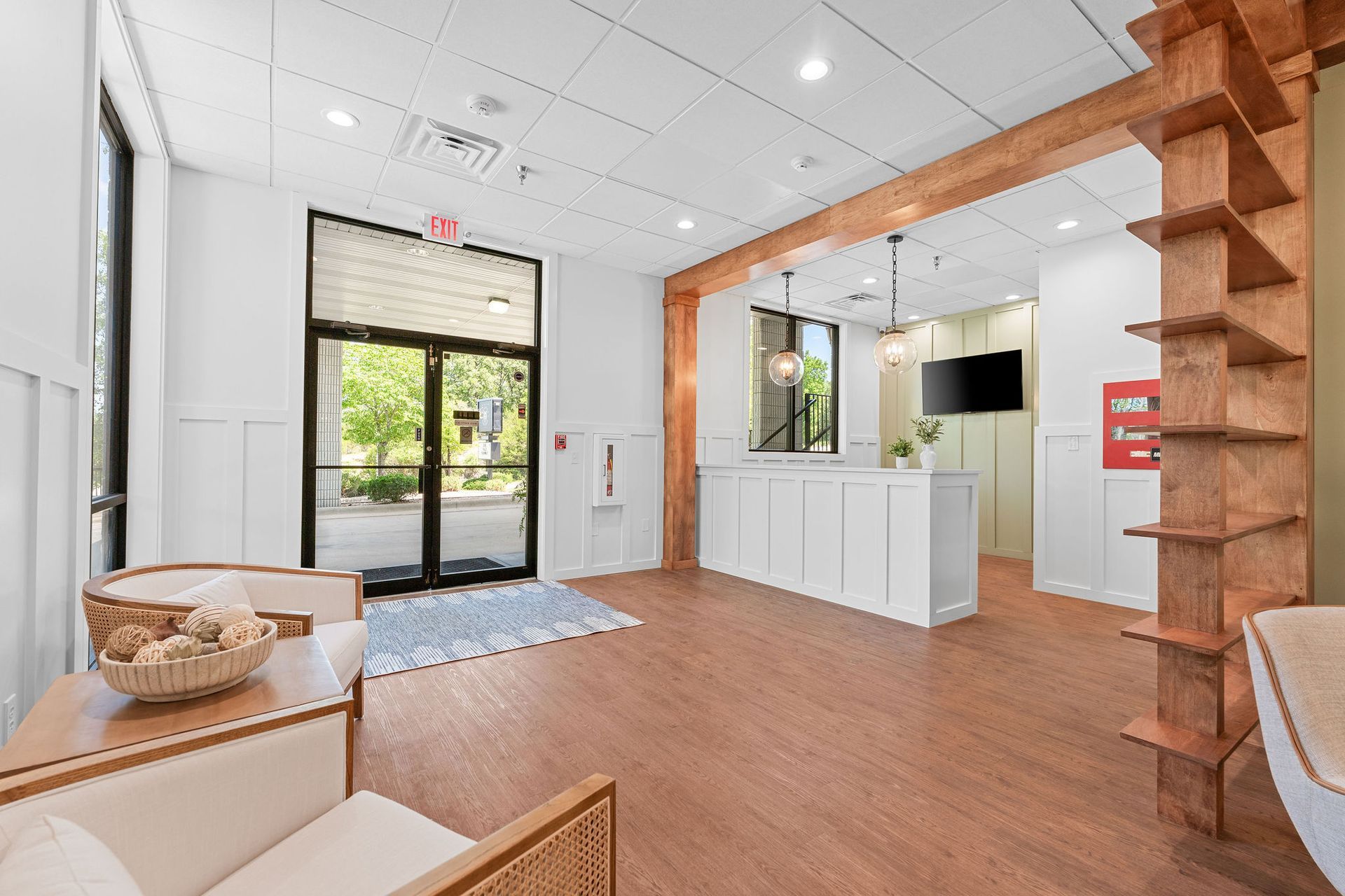 A living room with hardwood floors , a chair , a table and a television.