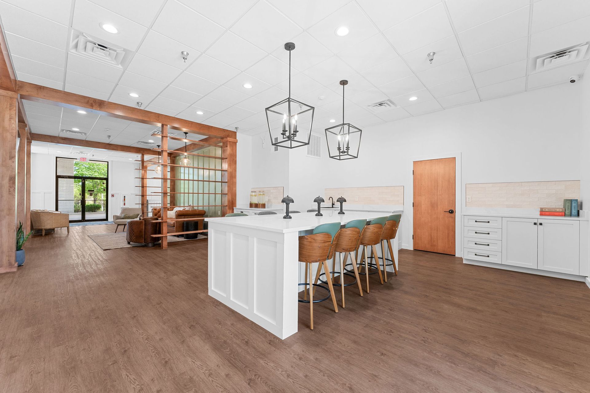 A kitchen with a large island and stools in a large room.