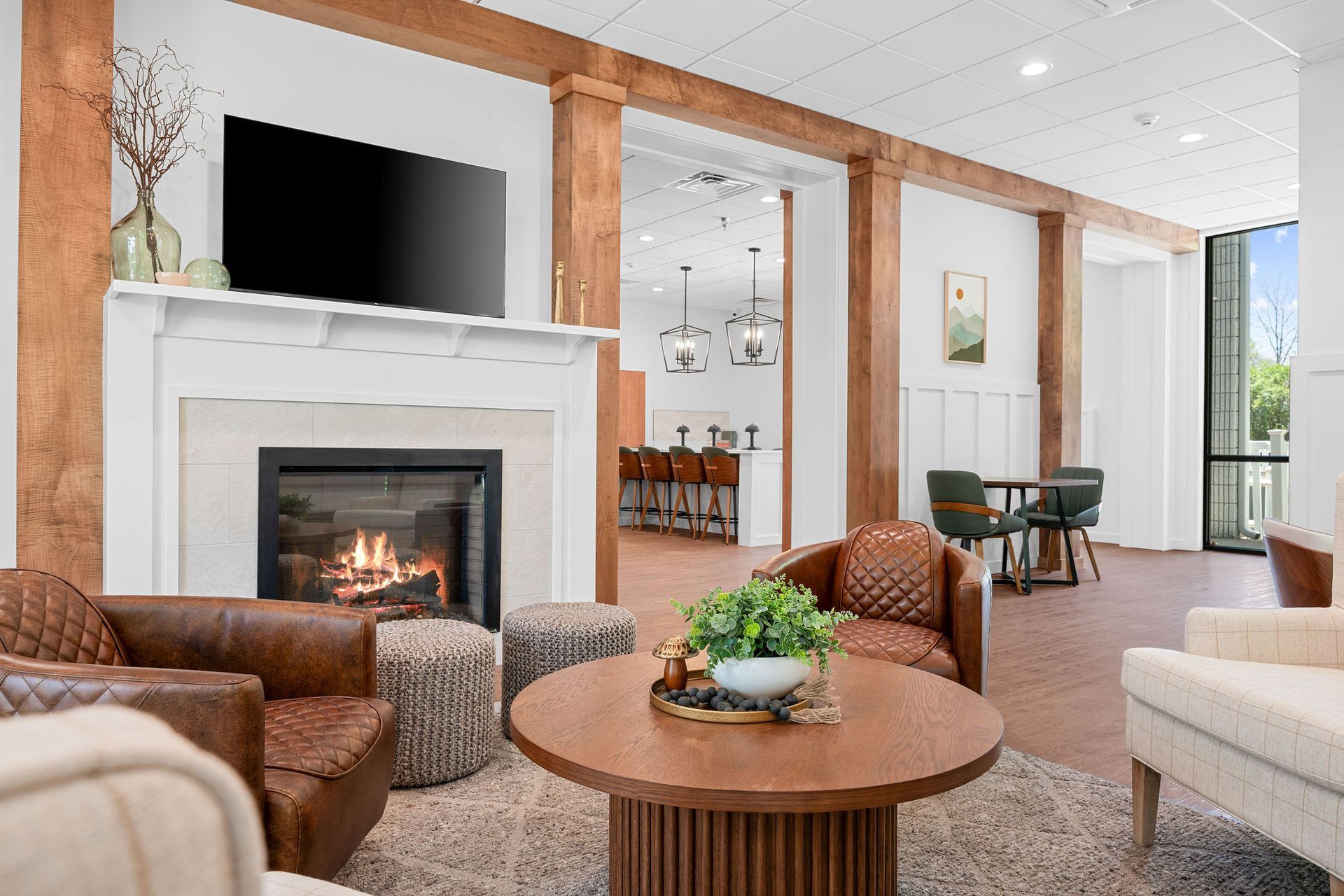 A living room with a fireplace , chairs , a table and a flat screen tv.