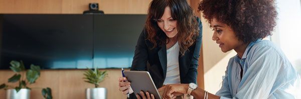 Two counselors reviewing a student record on a tablet