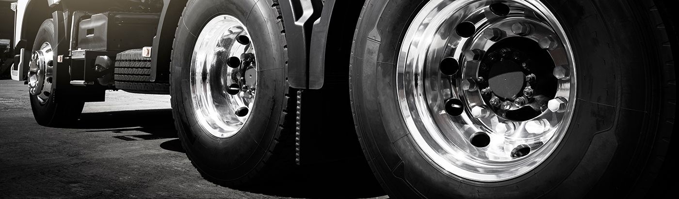 Close-up of truck tires. Black and white photo with shiny rims and dark tires on asphalt.