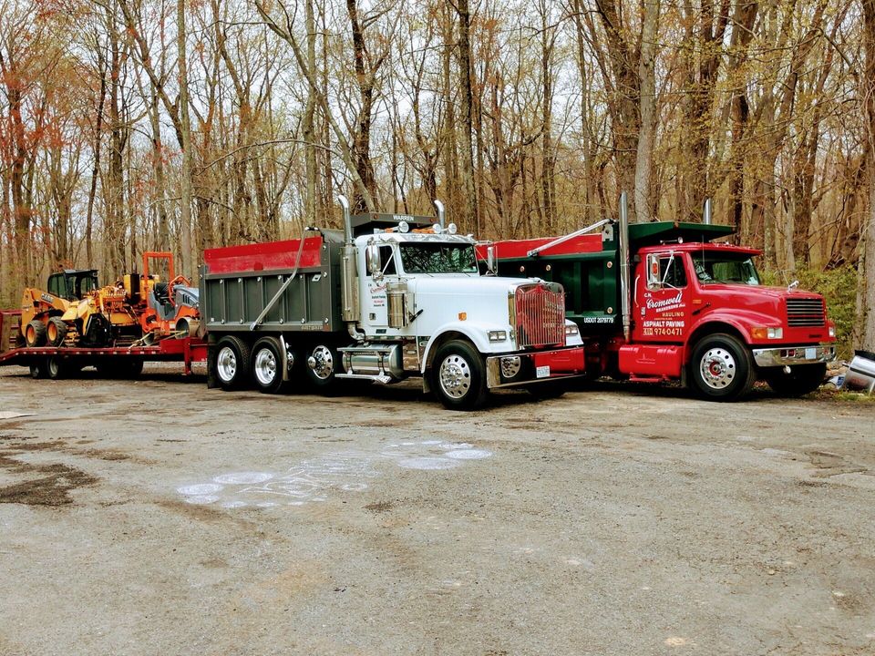 A red dump truck towing a green dump truck