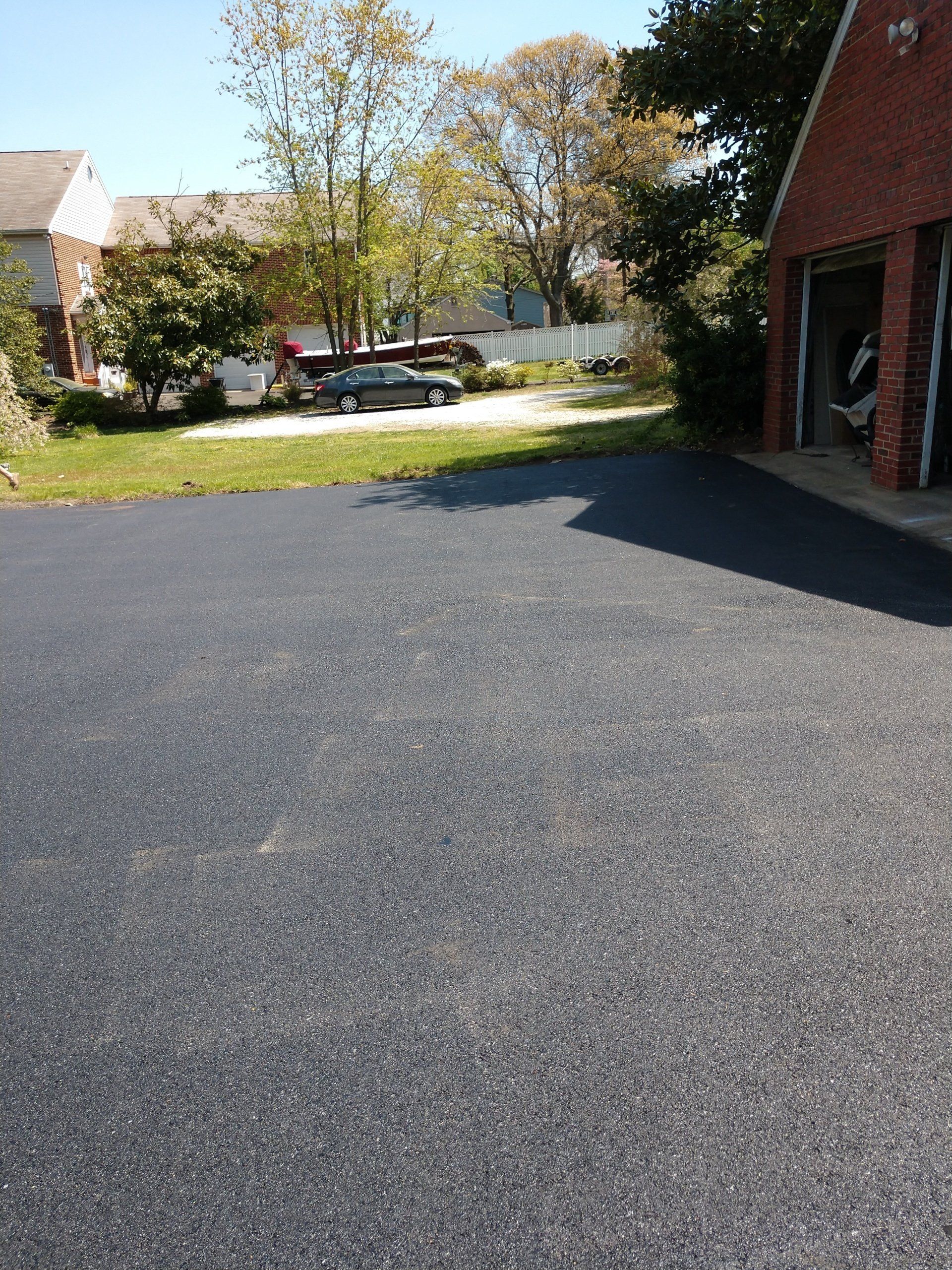 A black road with cars parked alongside in front of a commercial space, suggests a calm urban area