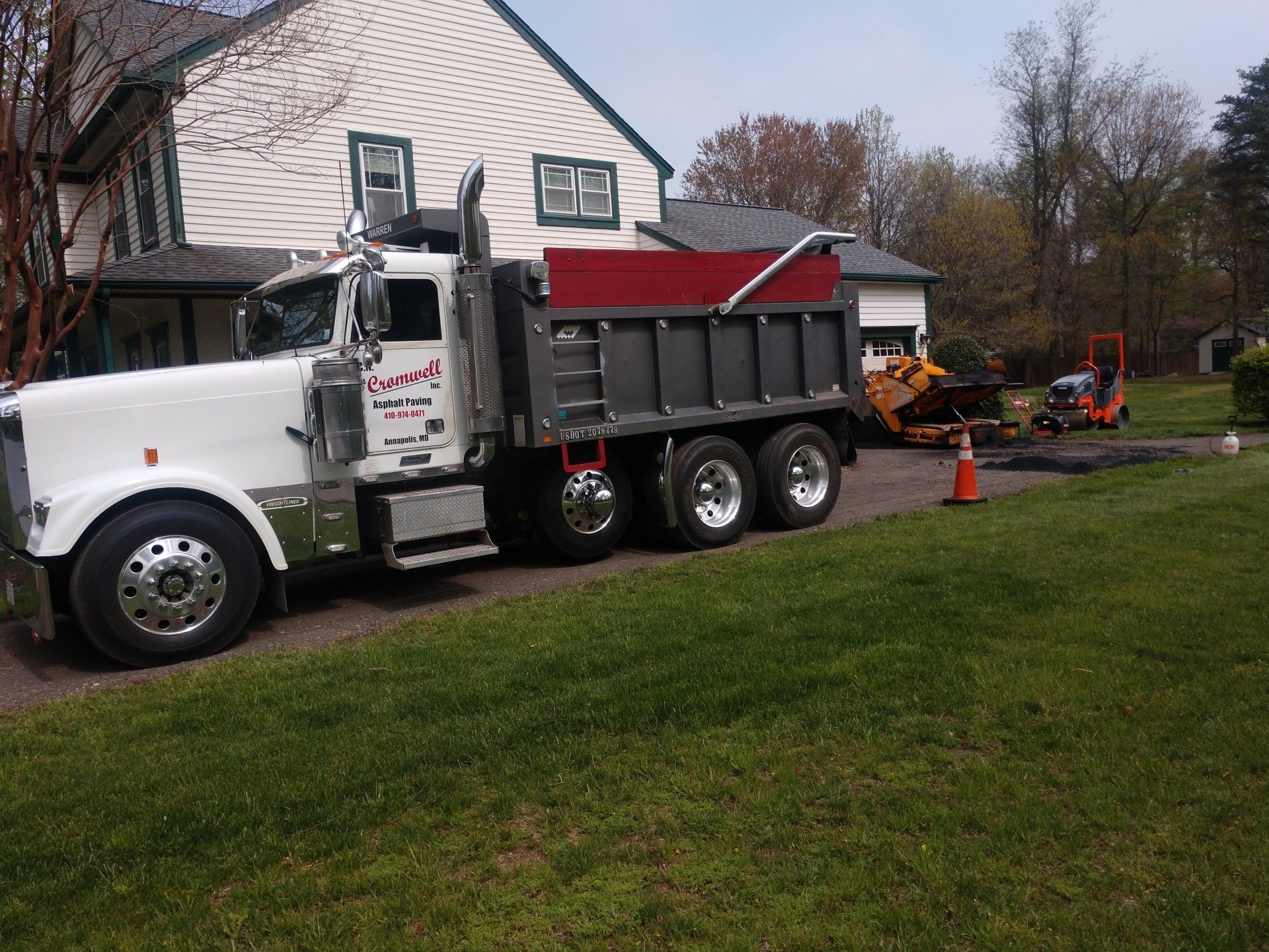 A hauling vehicle parked in front of a residential area, with maintenance work being conducted in the background