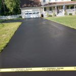 A calm residential area with a clean black road and garden areas on both sides, offering a peaceful environment