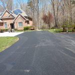 A calm residential area with a clean black road and garden areas on both sides, offering a peaceful environment