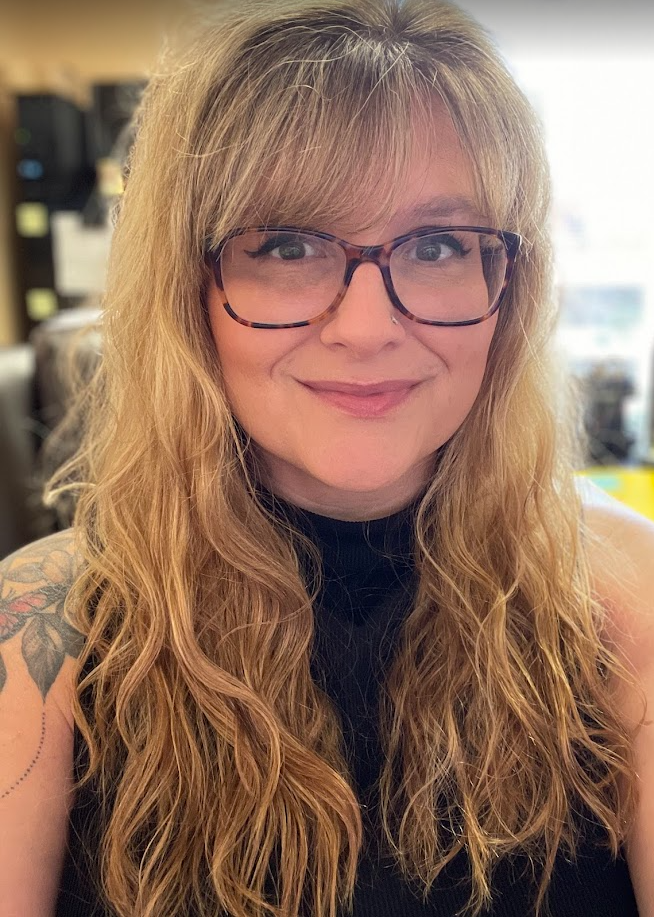 A woman wearing glasses and a black shirt is smiling for the camera.