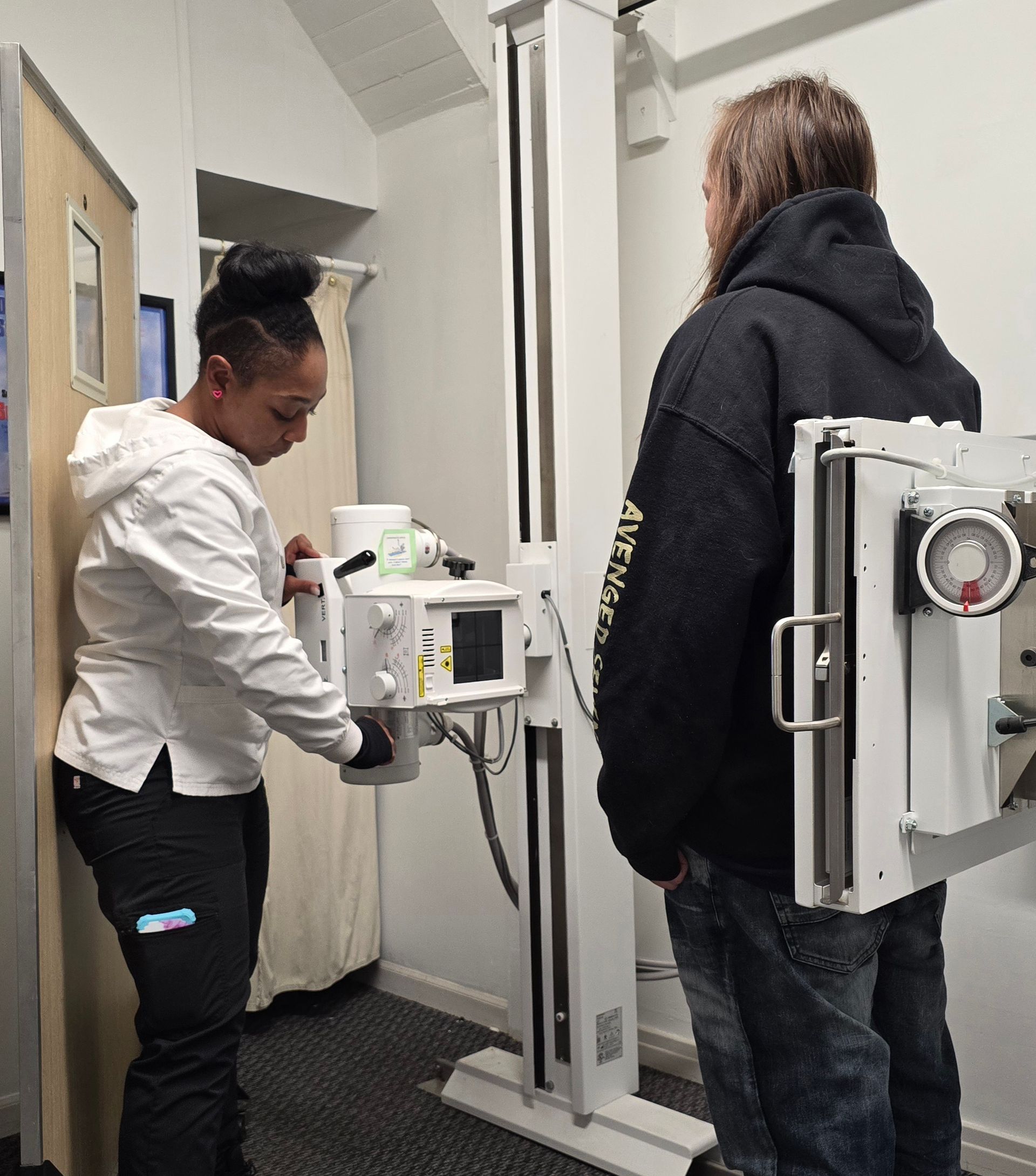 A man and a woman are standing in front of an x-ray machine.