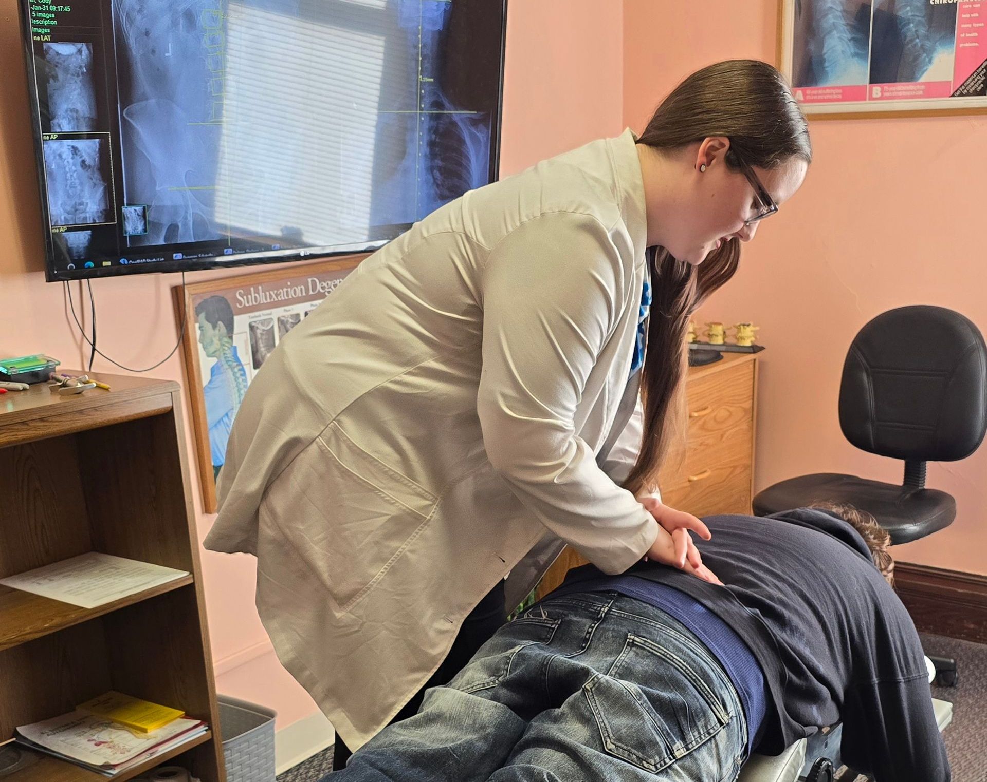 A woman is examining a man 's back in a room.
