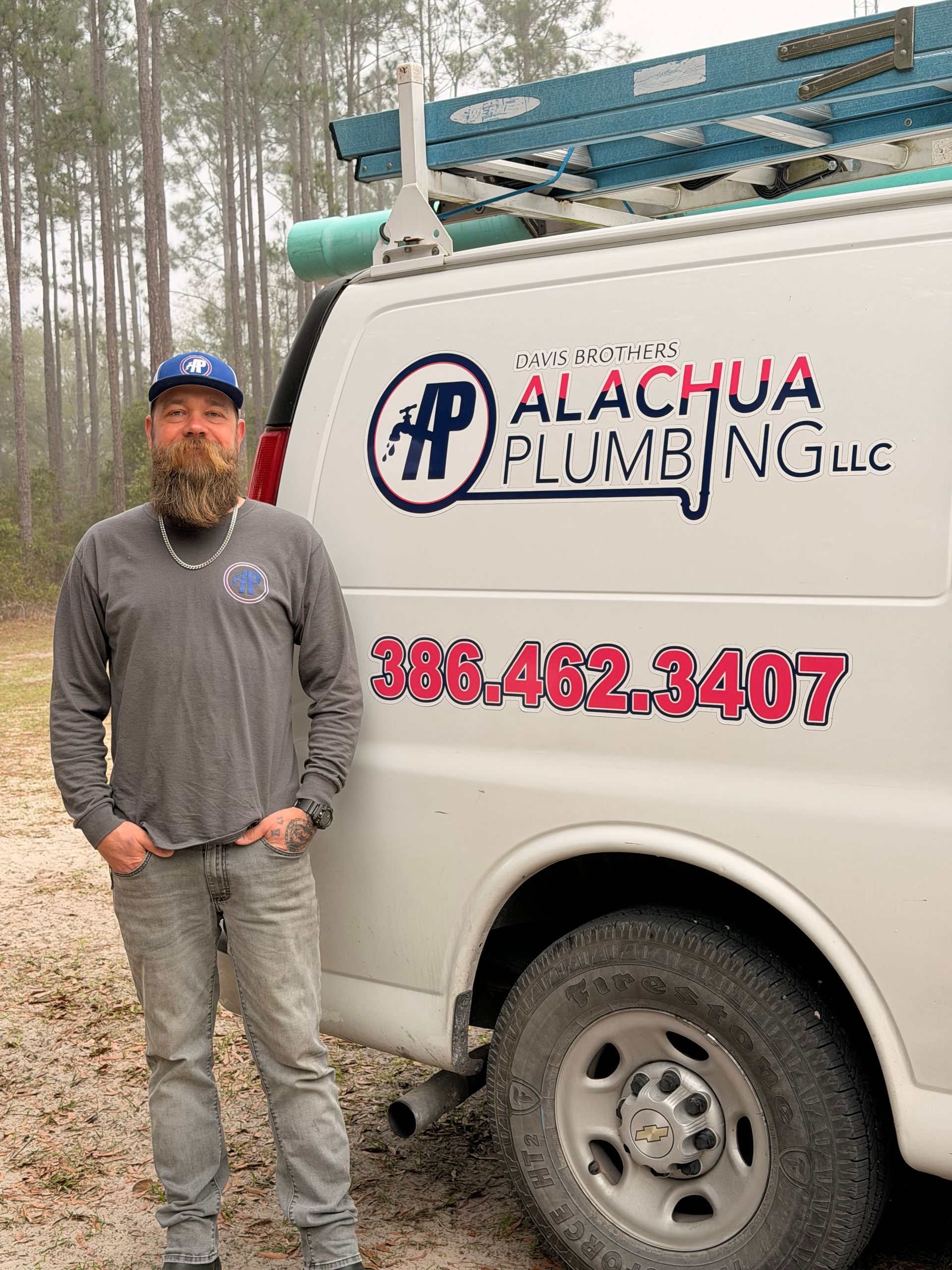 Man in front of a plumbing van, with company logo and phone number.