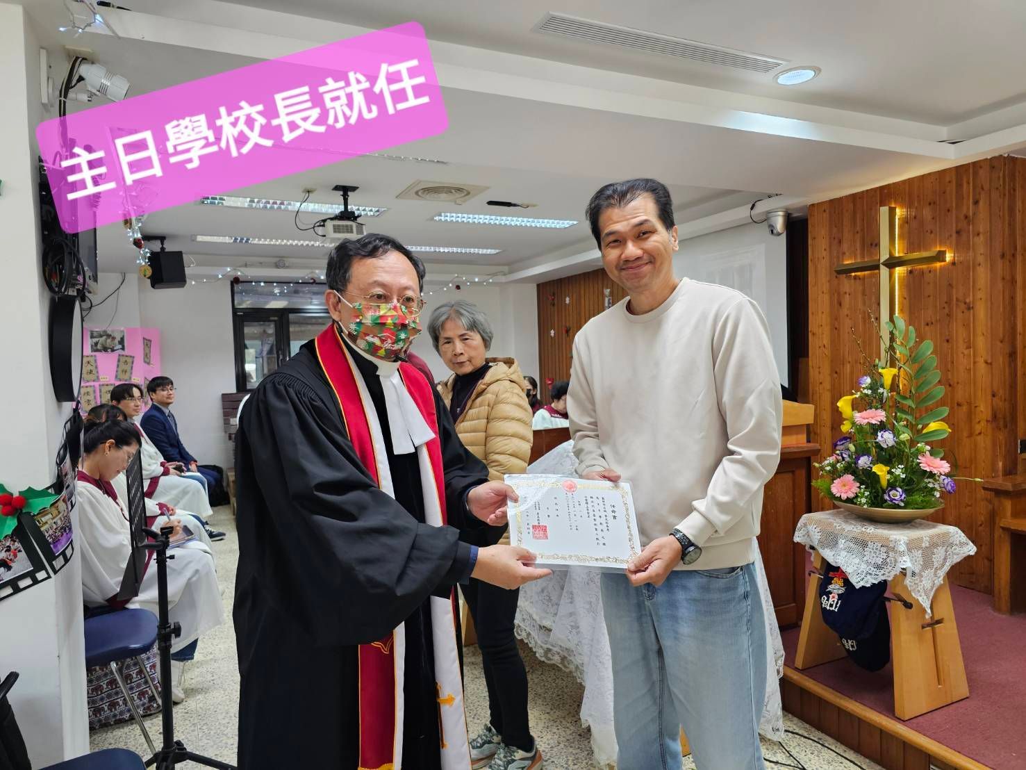 一位身穿长袍的牧师在教堂举行的主日学校校长就职典礼上向一名男子颁发证书。