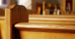 一张教堂木制长椅的特写镜头，拍摄角度略有不同，背景是模糊的室内景象。