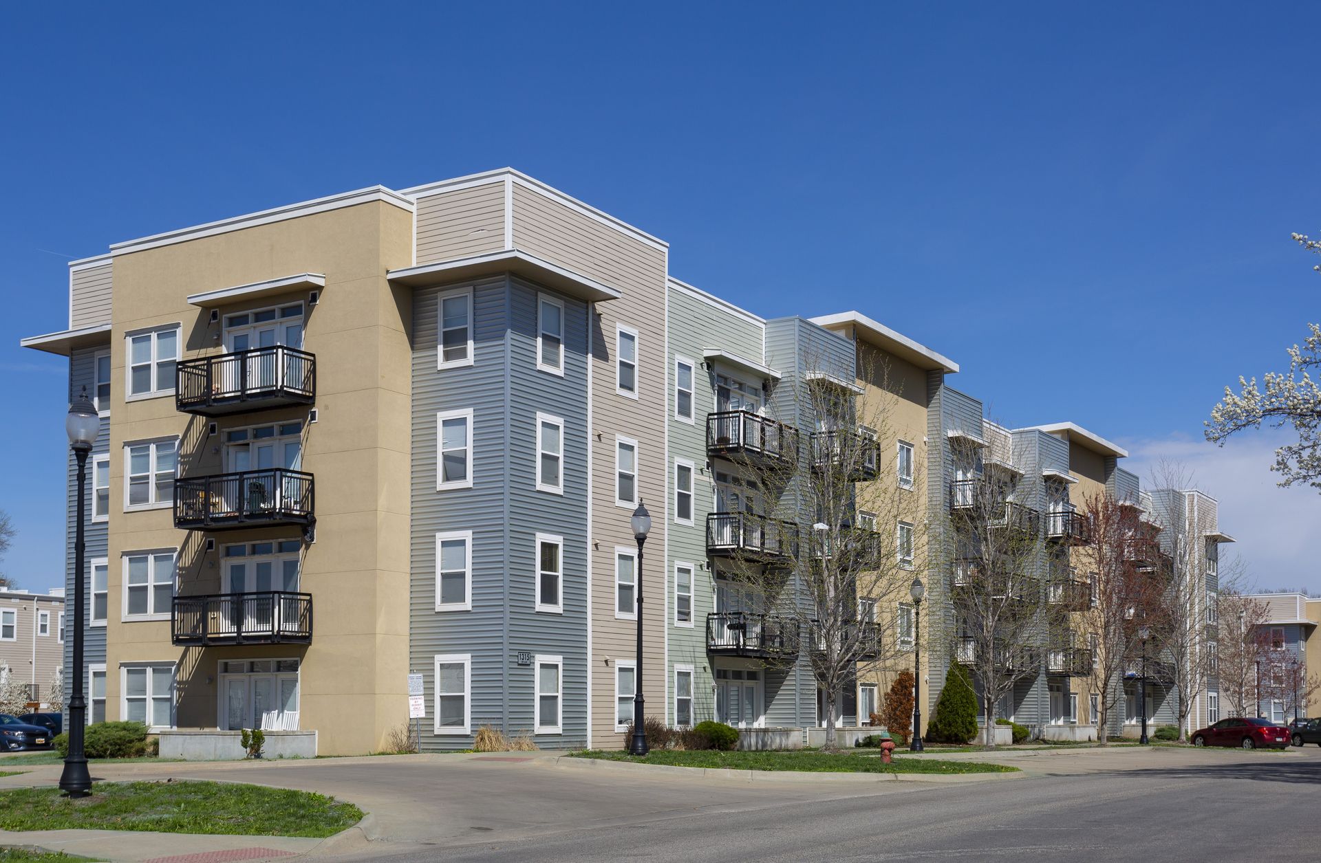 Apartment building with balconies, tan and silver facade, blue sky.
