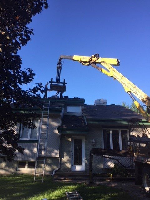Une grue jaune travaille sur le toit d'une maison