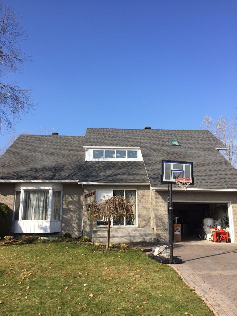 Une maison avec un panier de basket devant.