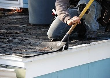 Un homme travaille sur un toit avec une pelle.