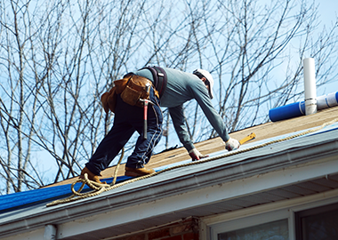 Un homme travaille sur le toit d'une maison.