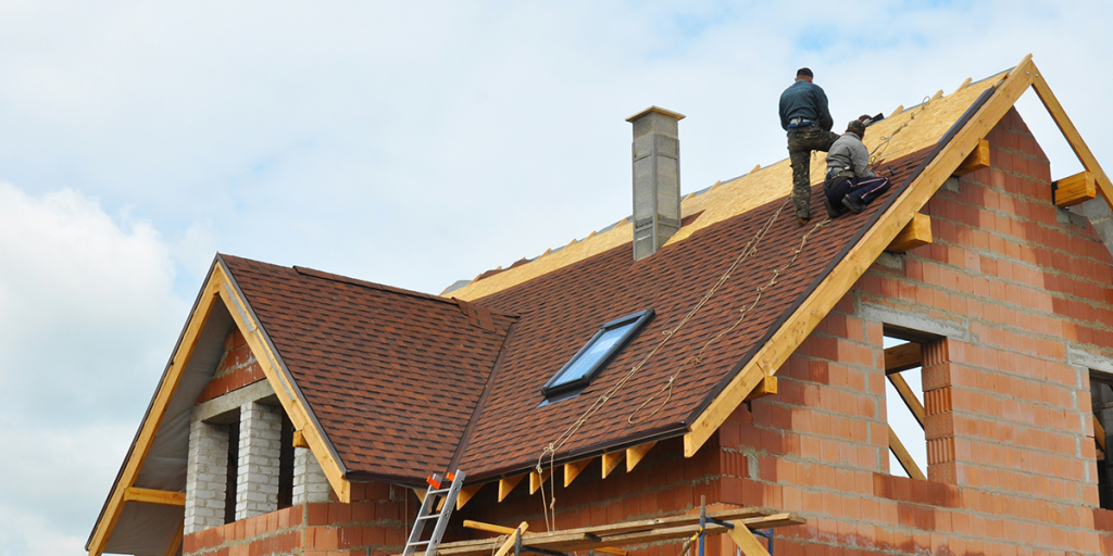 Un groupe d'hommes travaillent sur le toit d'une maison.