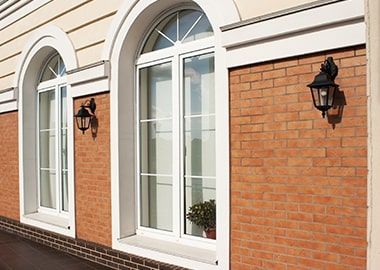 Un bâtiment en brique avec des fenêtres cintrées et des lanternes sur le côté.