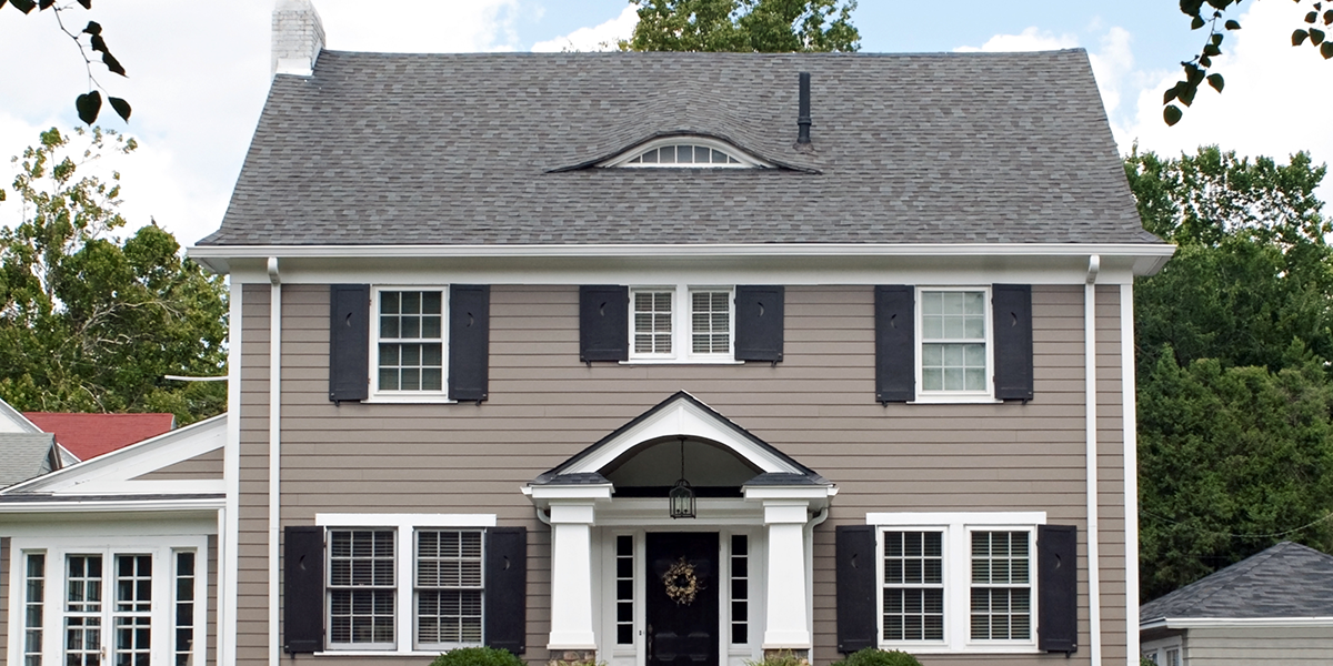 Une grande maison avec un toit gris et des volets noirs