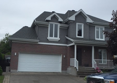 Une grande maison avec une porte de garage blanche et un camion bleu garé devant