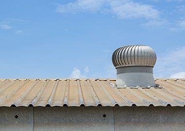 Un toit avec un ventilateur dessus et un ciel bleu en arrière-plan.