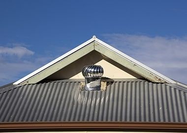 Un toit en métal surmonté d'un ventilateur.