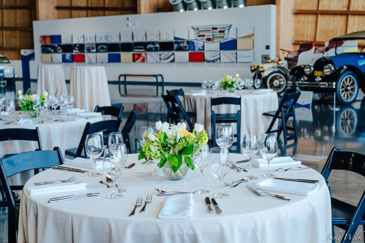 A table set for a wedding reception with a vase of flowers on it.