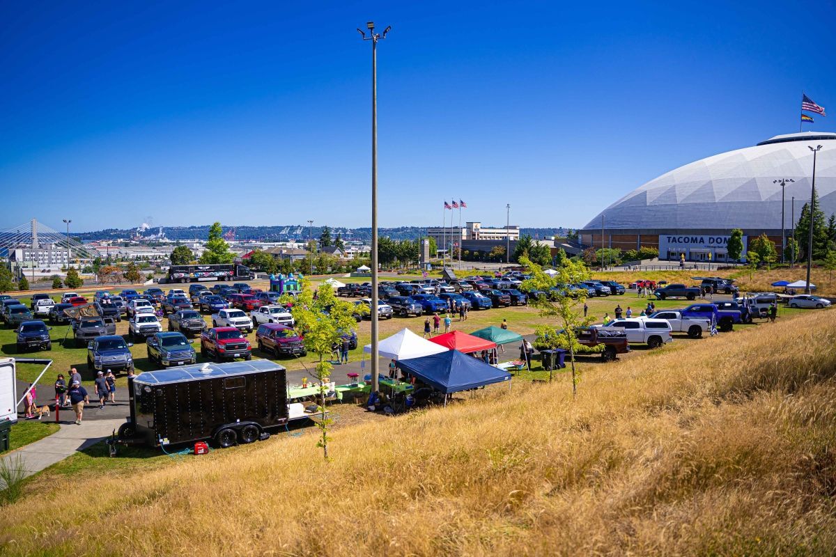 A lot of cars are parked in a parking lot in front of a dome.