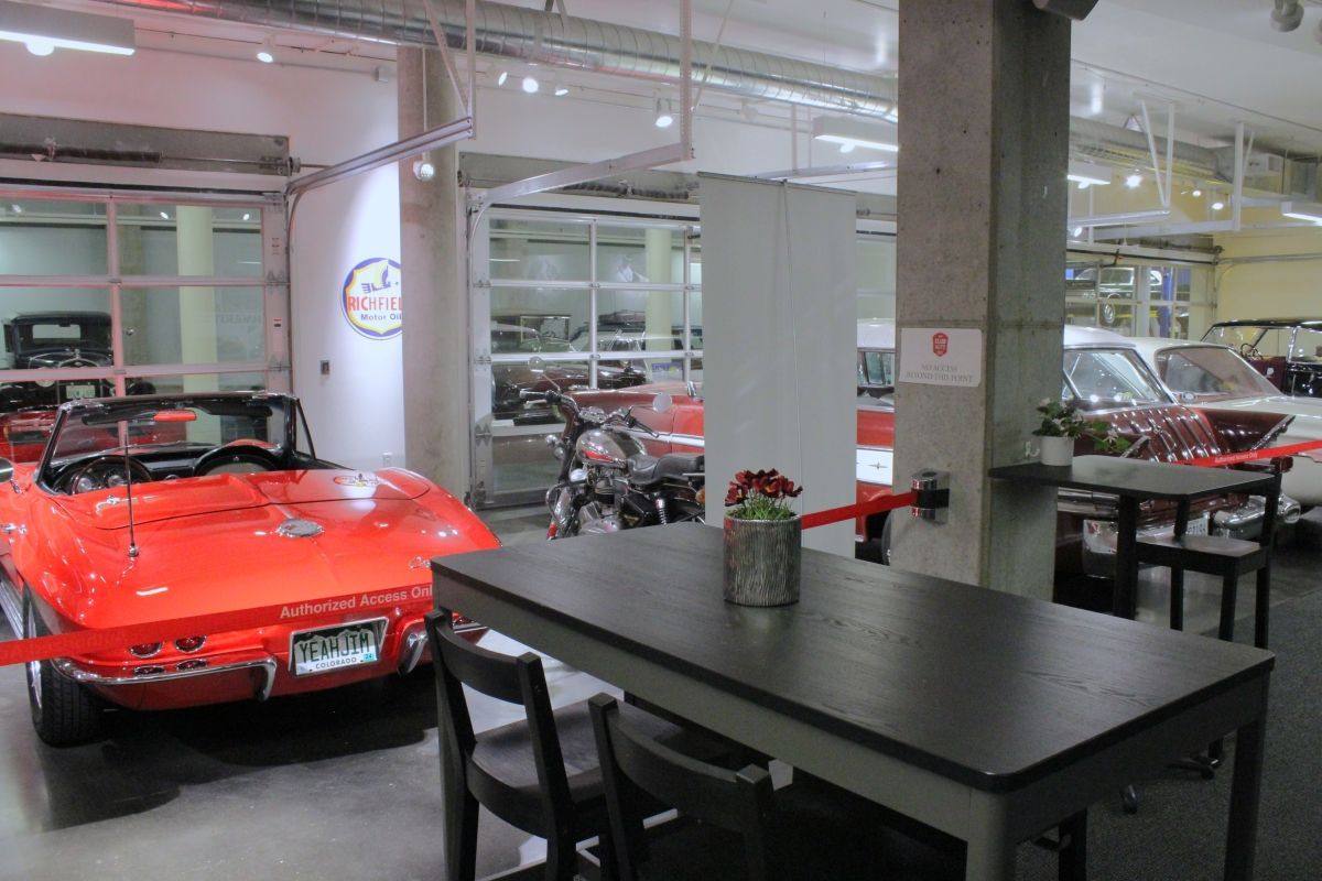 A red sports car is parked next to a table in a garage.