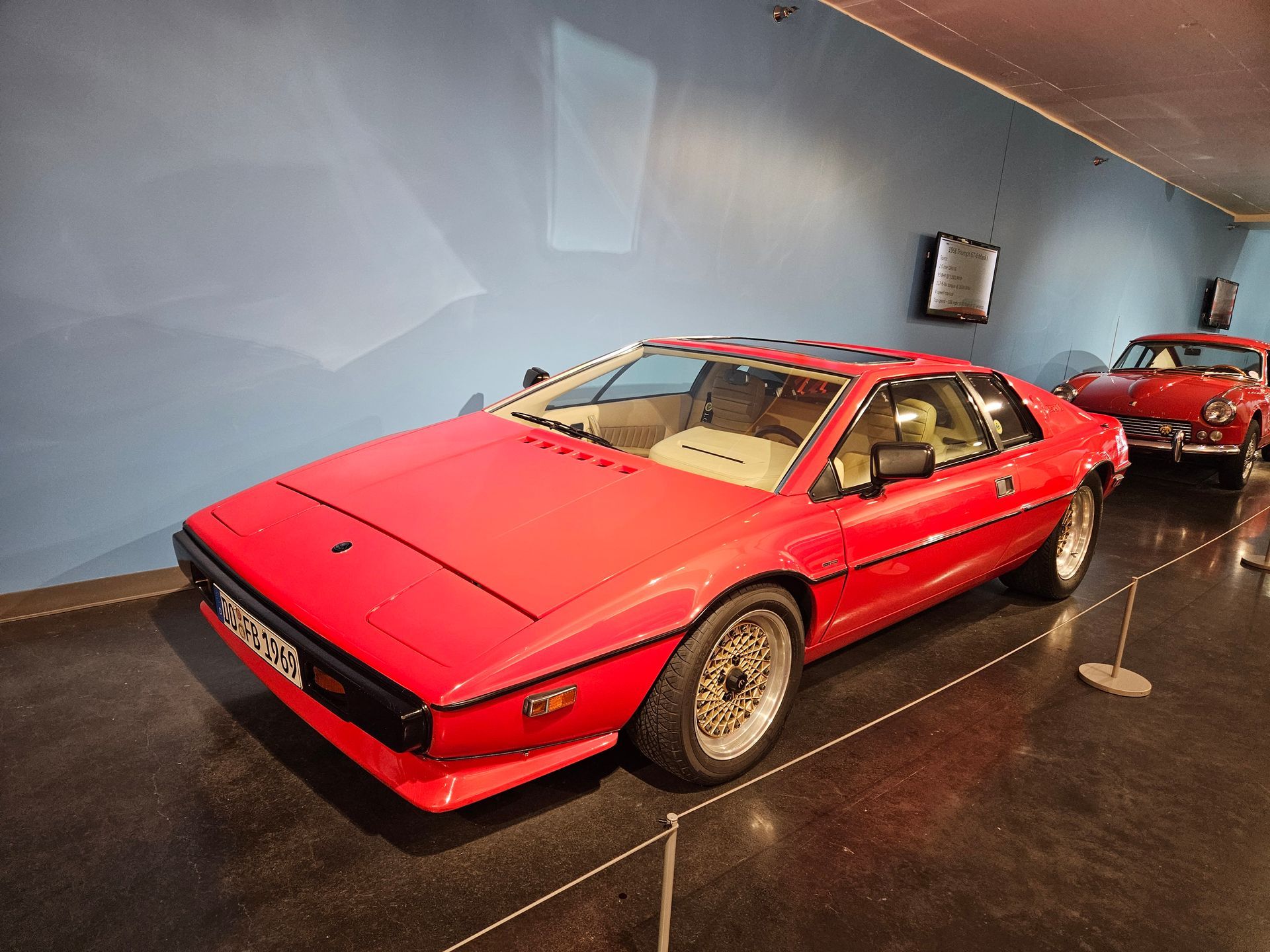 A red sports car is displayed in a museum