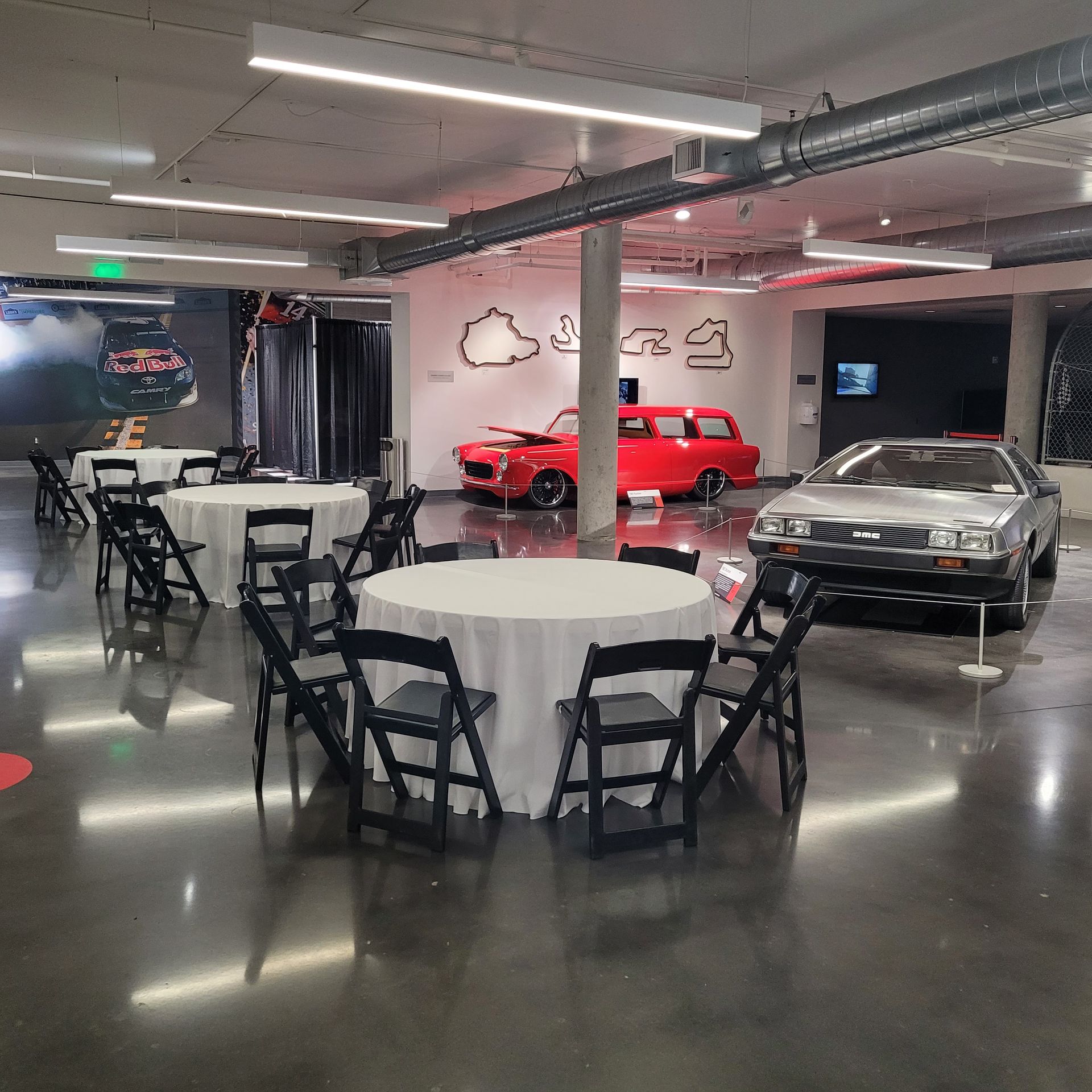 A room with tables and chairs and a car in the background