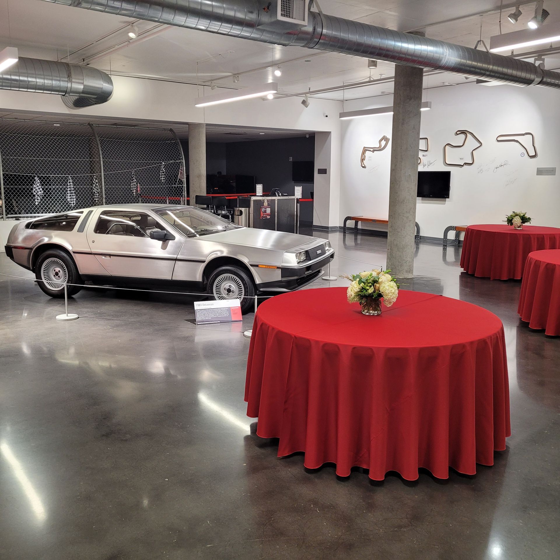 A silver car is parked in a room with red tables